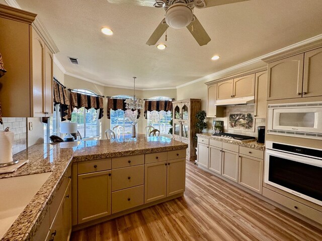 kitchen with appliances with stainless steel finishes, light hardwood / wood-style floors, ornamental molding, decorative backsplash, and sink