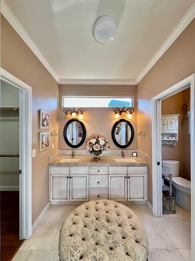 bathroom with toilet, plenty of natural light, ornamental molding, and vanity