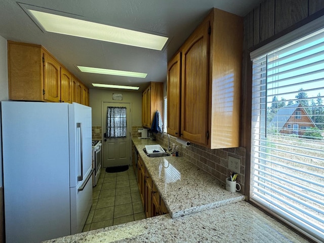 kitchen with sink, white appliances, light tile patterned flooring, and a wealth of natural light