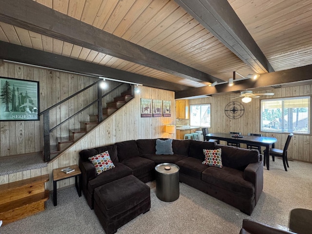 living room with beam ceiling, a healthy amount of sunlight, wooden walls, and light carpet