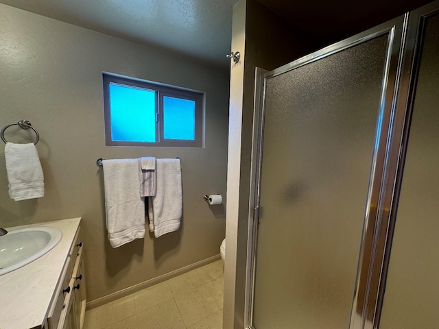 full bath featuring a shower stall, toilet, vanity, and baseboards