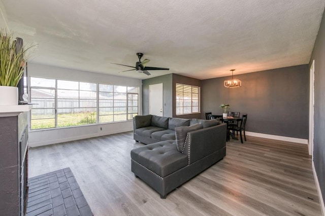 living room featuring ceiling fan with notable chandelier and hardwood / wood-style floors