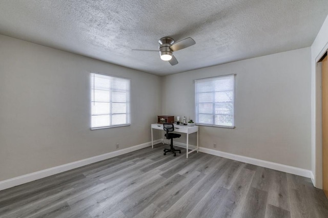 unfurnished office with light wood-type flooring, ceiling fan, a textured ceiling, and plenty of natural light