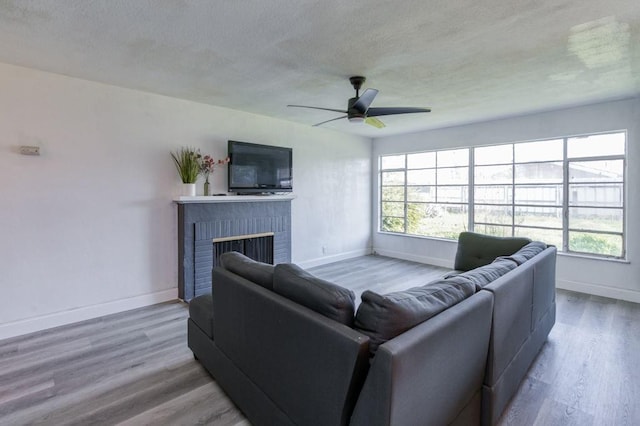 living room featuring ceiling fan, a fireplace, and hardwood / wood-style flooring