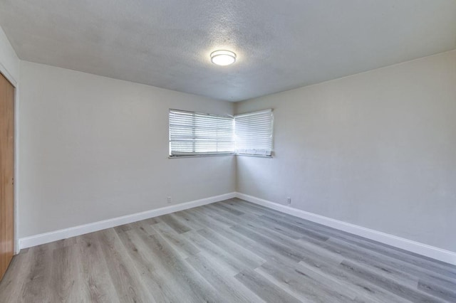 spare room with light hardwood / wood-style floors and a textured ceiling