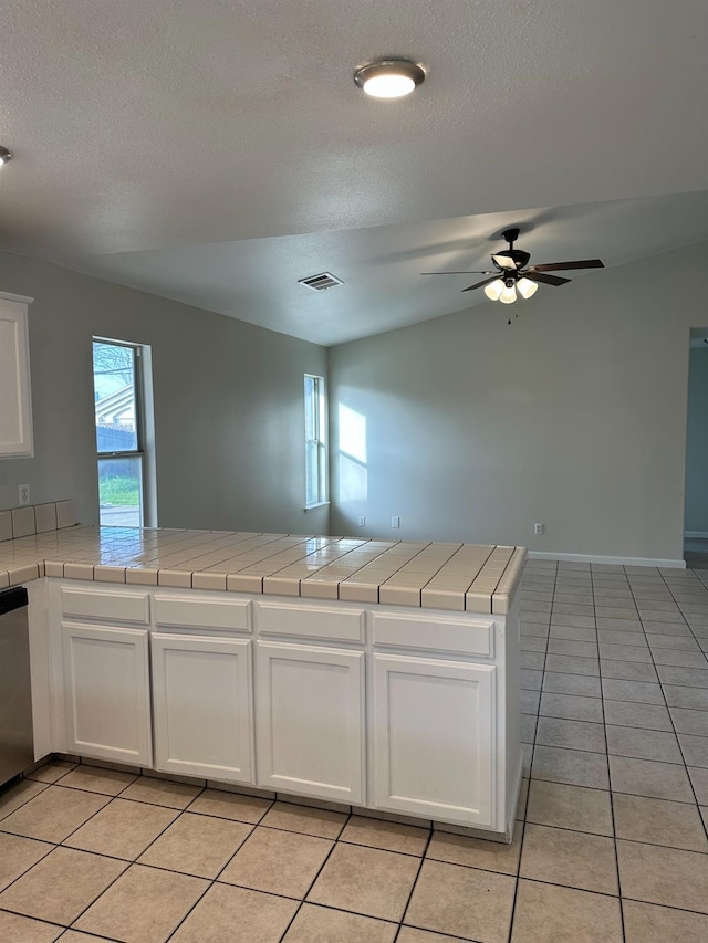 kitchen featuring kitchen peninsula, tile countertops, light tile patterned floors, and white cabinetry