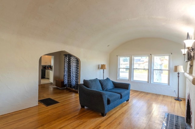 living room featuring hardwood / wood-style flooring, brick ceiling, and lofted ceiling