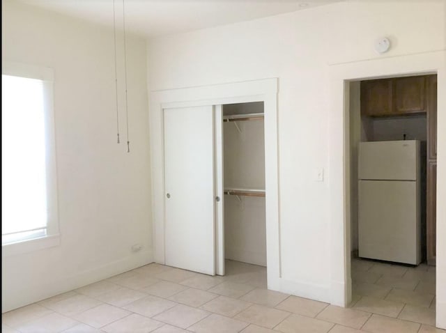 unfurnished bedroom featuring white fridge and a closet