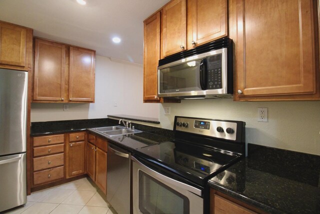 kitchen featuring sink, appliances with stainless steel finishes, dark stone countertops, and light tile patterned floors