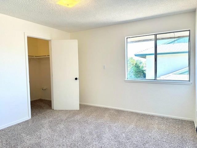 unfurnished bedroom featuring a closet, multiple windows, a textured ceiling, and a spacious closet