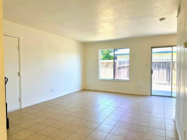 spare room with a textured ceiling and light tile patterned floors