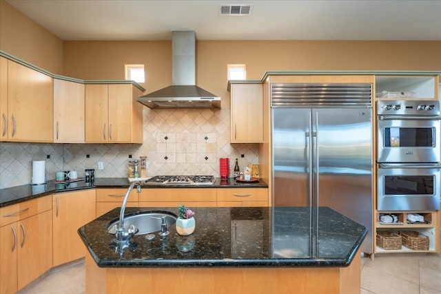 kitchen with stainless steel appliances, an island with sink, sink, and wall chimney exhaust hood