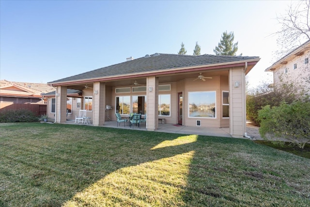 rear view of house with a patio, ceiling fan, and a lawn