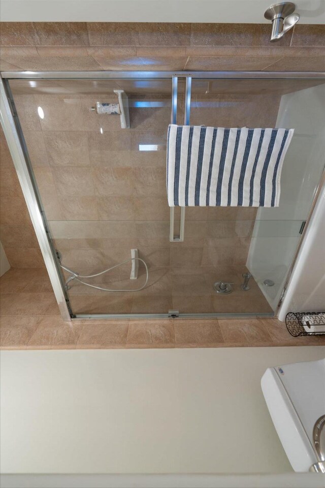 bathroom featuring combined bath / shower with glass door and toilet