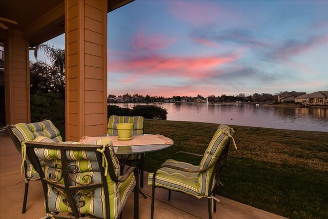 patio terrace at dusk with a yard and a water view