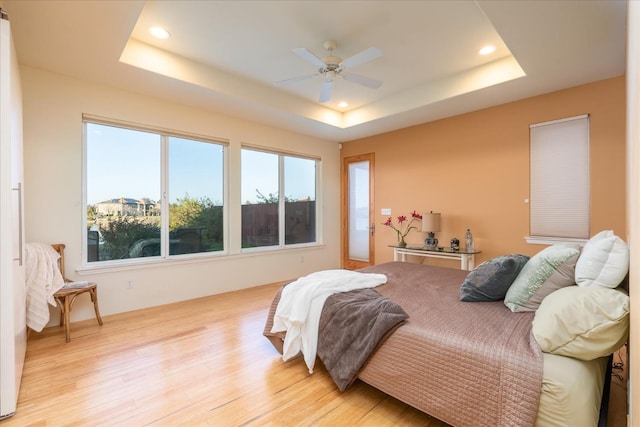 bedroom featuring a raised ceiling, ceiling fan, and light hardwood / wood-style floors