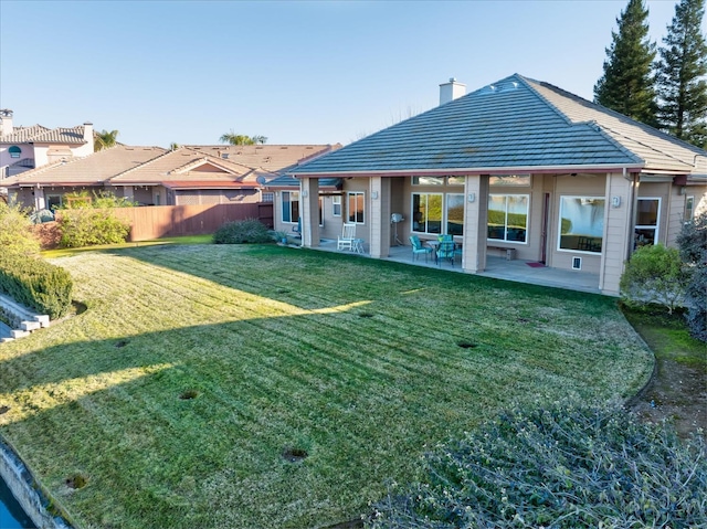 rear view of property with a patio and a lawn