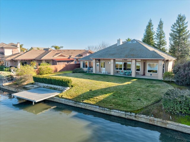 rear view of house featuring a patio, a lawn, and a water view