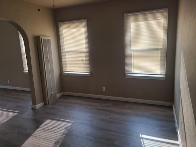 empty room with a wealth of natural light and dark hardwood / wood-style floors