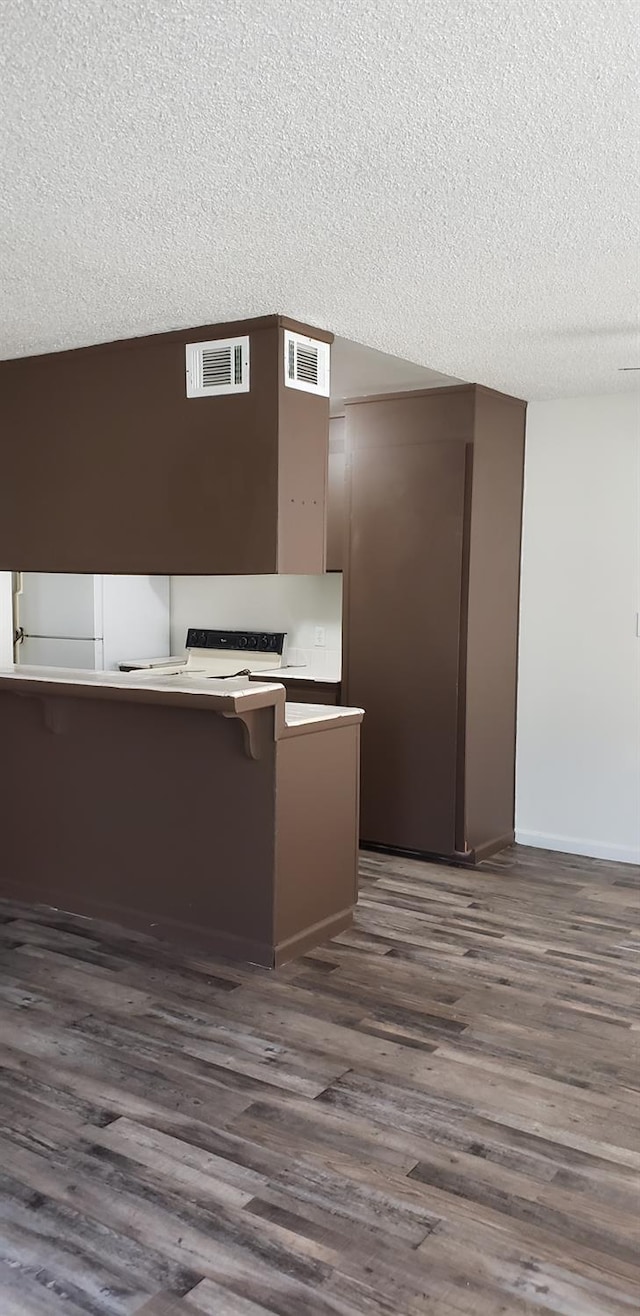 kitchen with a textured ceiling, dark hardwood / wood-style flooring, and kitchen peninsula