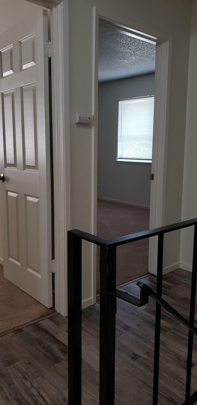 hallway featuring a textured ceiling and dark hardwood / wood-style flooring