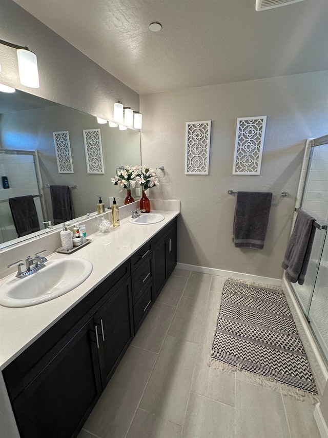 bathroom with an enclosed shower, vanity, and a textured ceiling