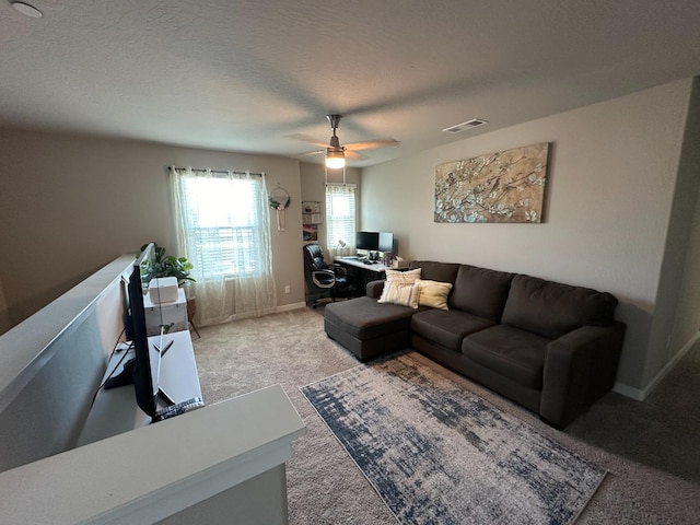 living room featuring ceiling fan, light carpet, and a textured ceiling