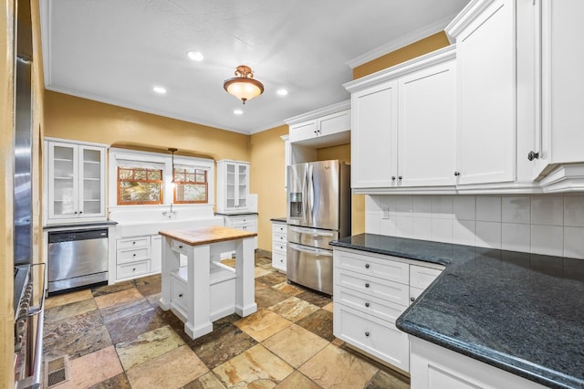 kitchen with stainless steel appliances, crown molding, butcher block countertops, white cabinets, and backsplash