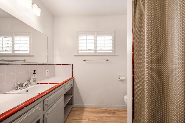 bathroom with toilet, vanity, backsplash, and hardwood / wood-style floors