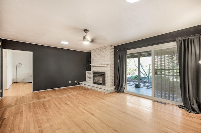 unfurnished living room featuring a fireplace, light wood-type flooring, and ceiling fan