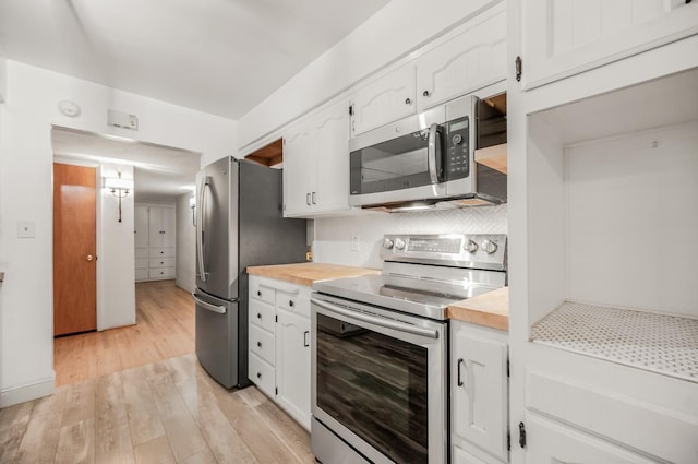 kitchen with wooden counters, white cabinetry, appliances with stainless steel finishes, light hardwood / wood-style flooring, and tasteful backsplash