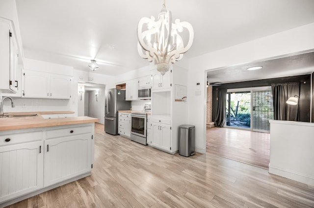 kitchen featuring appliances with stainless steel finishes, pendant lighting, white cabinetry, and wood counters