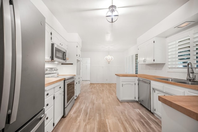 kitchen featuring pendant lighting, stainless steel appliances, wooden counters, white cabinets, and sink