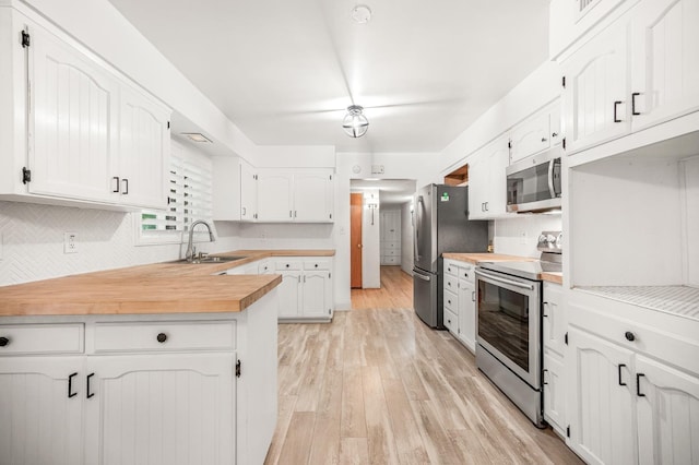 kitchen featuring stainless steel appliances, tasteful backsplash, light wood-type flooring, white cabinets, and sink