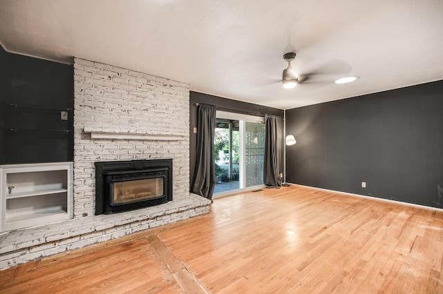 unfurnished living room with a brick fireplace, ceiling fan, and wood-type flooring