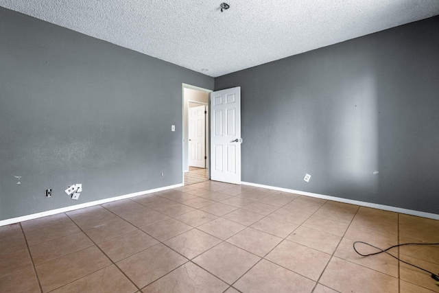 spare room with a textured ceiling and light tile patterned floors