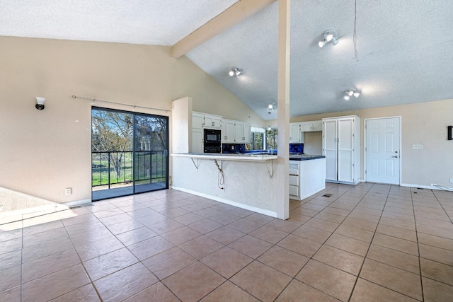 kitchen with white cabinets, tile patterned flooring, kitchen peninsula, a breakfast bar area, and beam ceiling