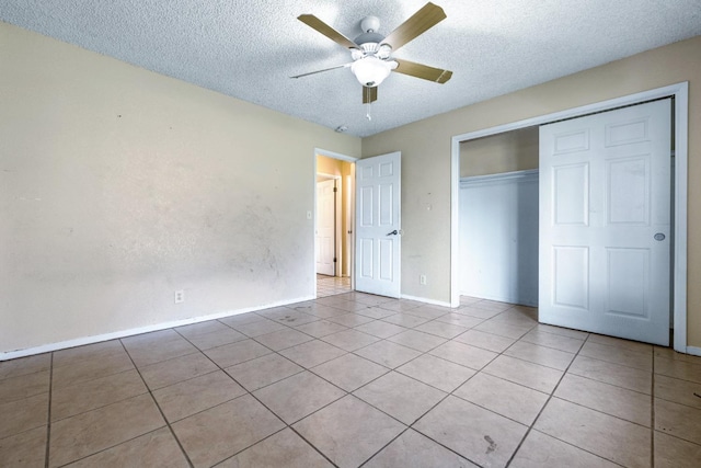 unfurnished bedroom featuring a closet, a textured ceiling, ceiling fan, and light tile patterned floors