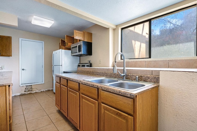 kitchen with sink, range, a textured ceiling, and light tile patterned floors