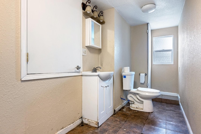 bathroom featuring toilet, a textured ceiling, and vanity