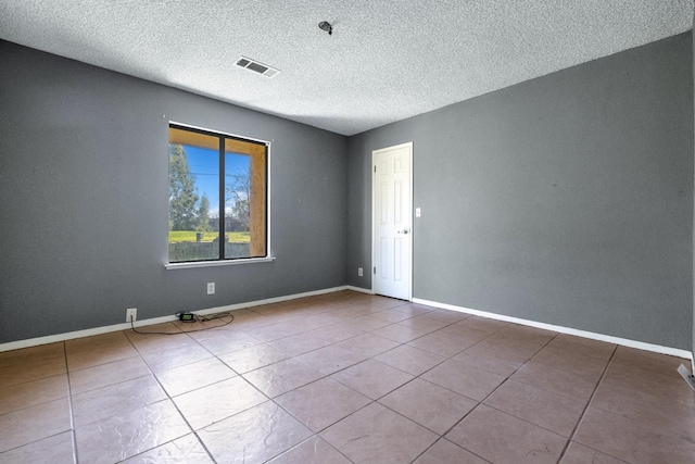 tiled empty room featuring a textured ceiling