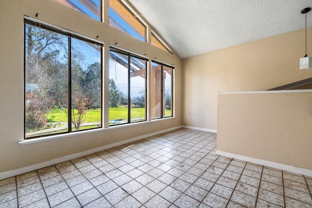 tiled empty room with a textured ceiling, vaulted ceiling, and plenty of natural light