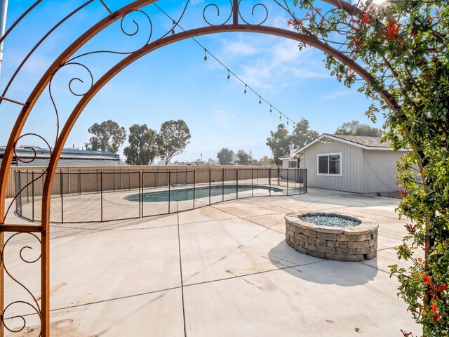 view of patio with a fenced in pool, fence, and a fire pit