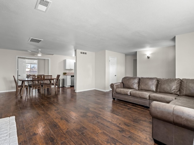 living room featuring dark wood-style floors, baseboards, and visible vents