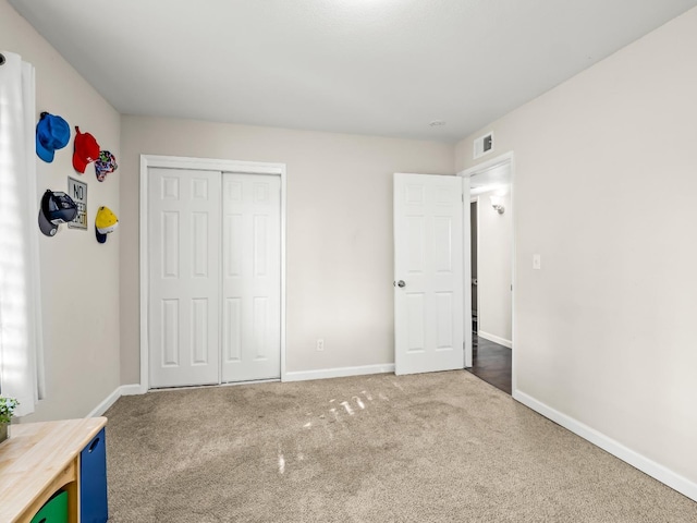 unfurnished bedroom featuring a closet, carpet flooring, visible vents, and baseboards