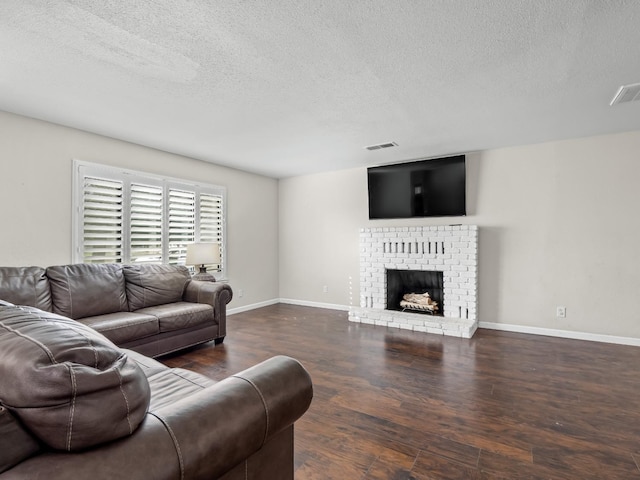 living room with baseboards, visible vents, wood finished floors, a textured ceiling, and a fireplace