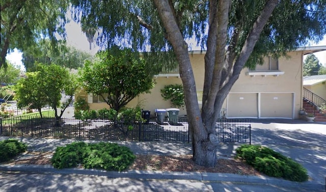 view of property hidden behind natural elements featuring a garage