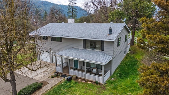 rear view of house featuring a yard, covered porch, a garage, and a mountain view