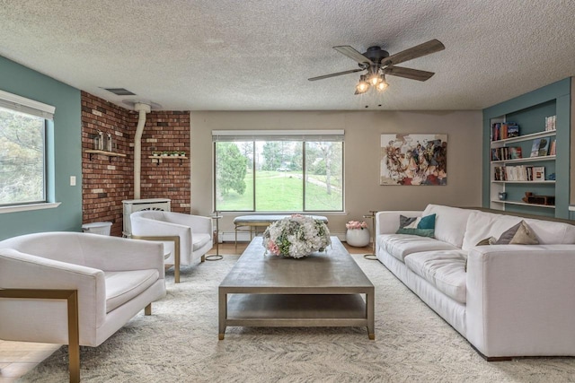 living room featuring a textured ceiling, ceiling fan, and a wood stove