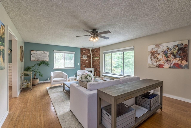 living room featuring ceiling fan, a healthy amount of sunlight, light wood-type flooring, and a textured ceiling